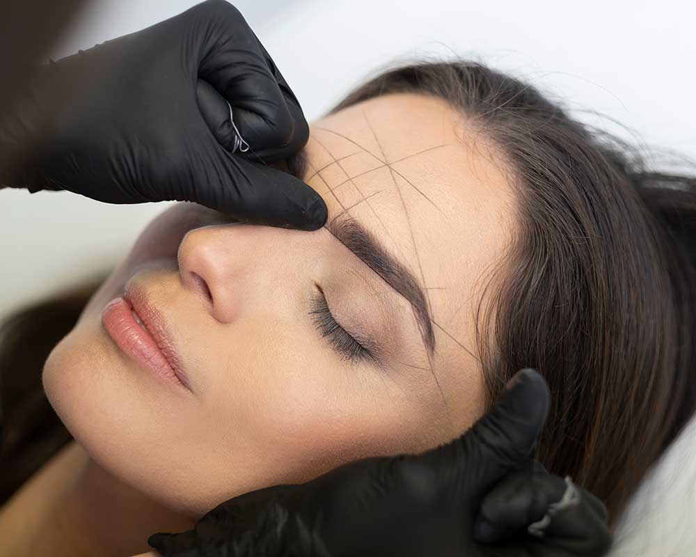 Woman receiving a threading eyebrow treatment.